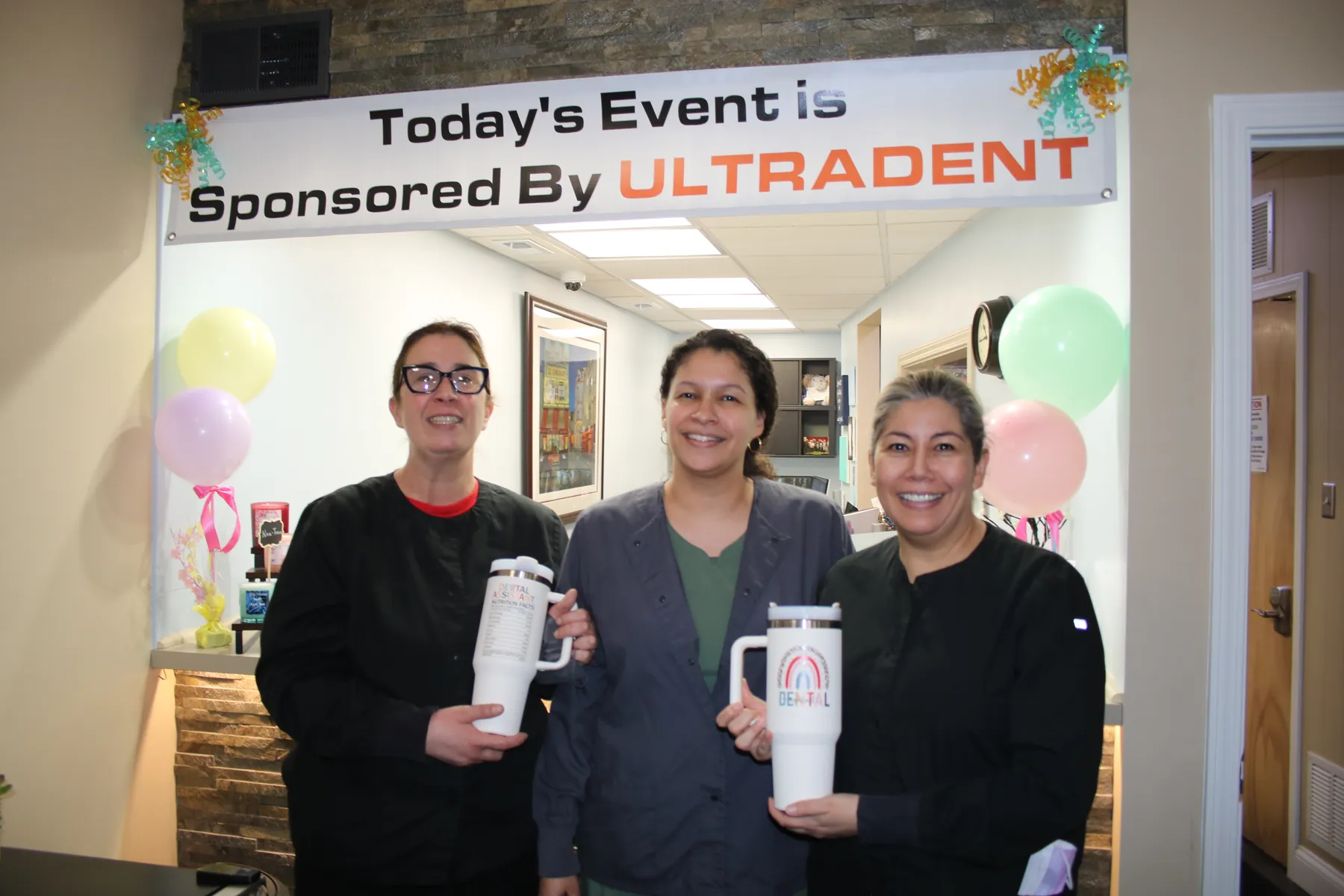 Three members of the dental team beneath the Ultradent sponsor banner